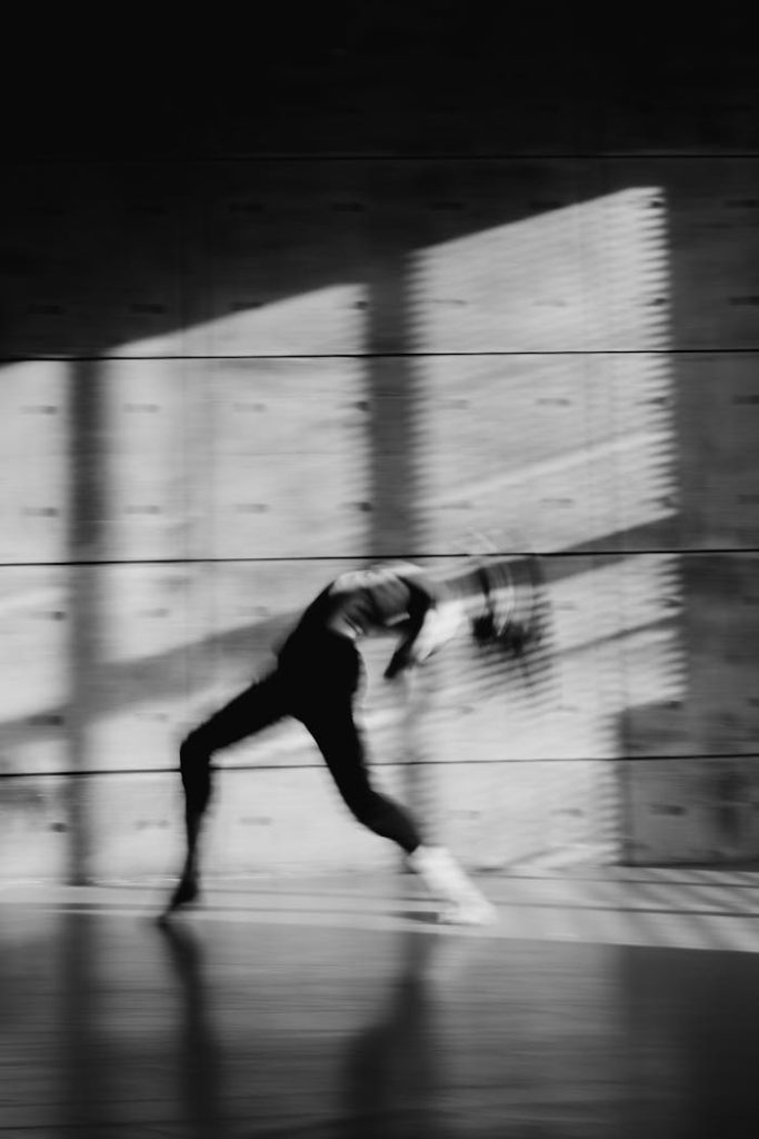 Black and white artistic motion blur of a dancer performing indoors, emphasizing dynamic movement.