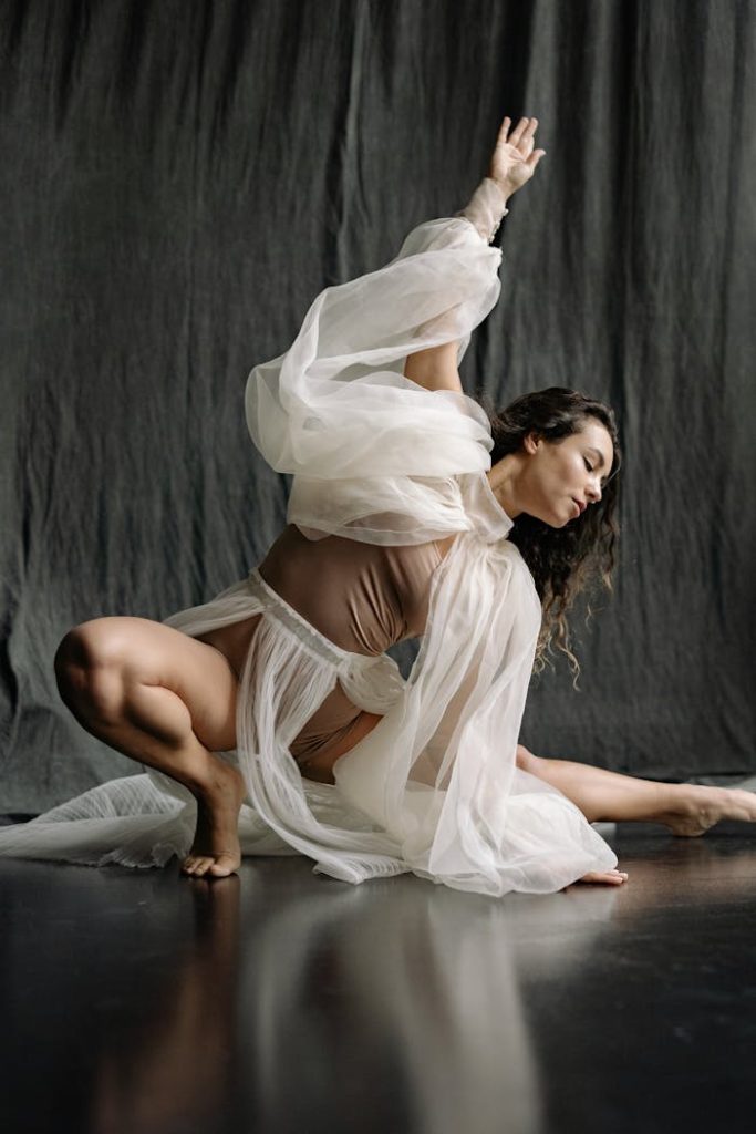 Elegant dancer in flowing costume striking a pose in a studio environment.